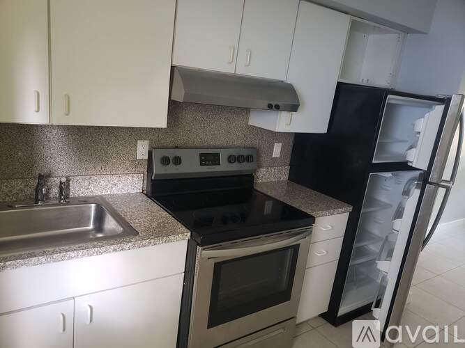 A kitchen with white cabinets and a black fridge.