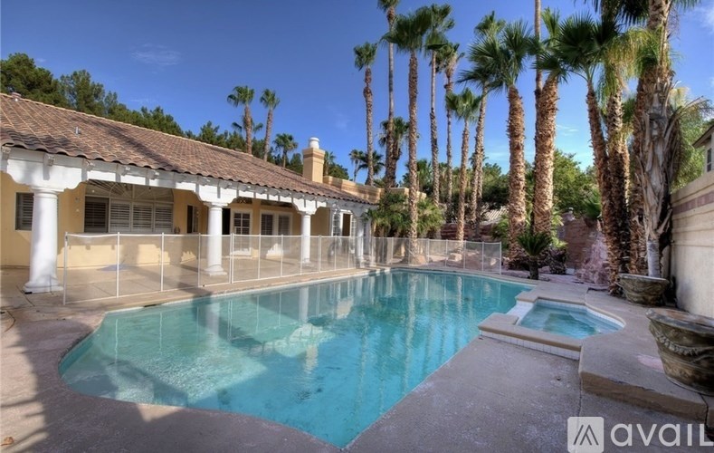 A pool surrounded by palm trees and a building with columns.