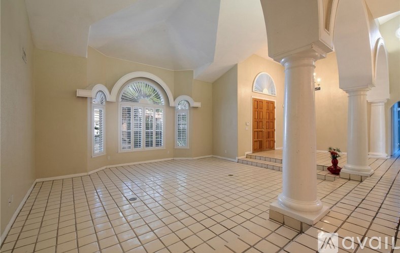 A spacious room with white columns and a tiled floor.