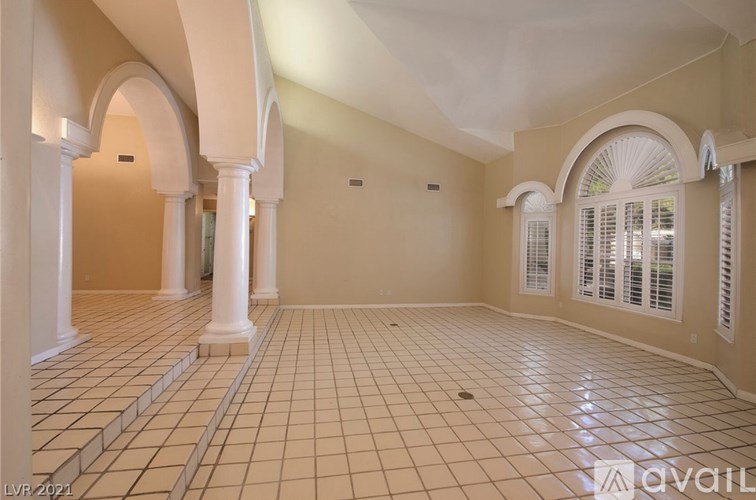 A spacious room with arched columns and tiled flooring.
