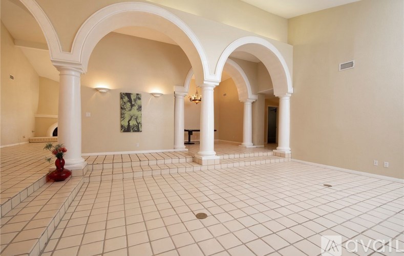 A spacious room with arched columns and a tiled floor.