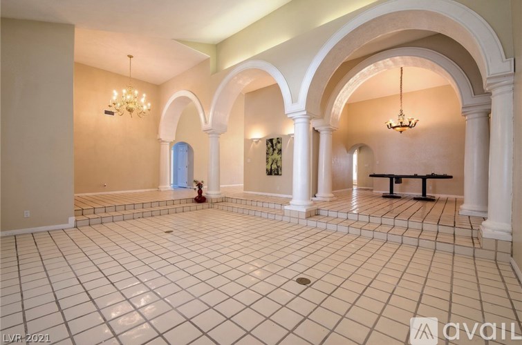 A spacious room with arched columns and a chandelier.