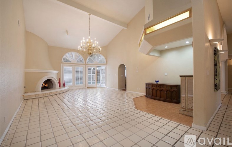 A spacious room with a fireplace and a chandelier.