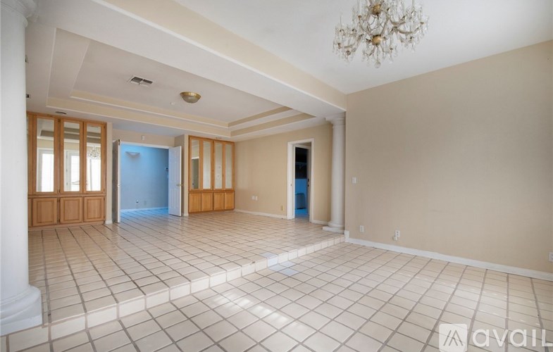 A spacious room with a chandelier and tiled flooring.