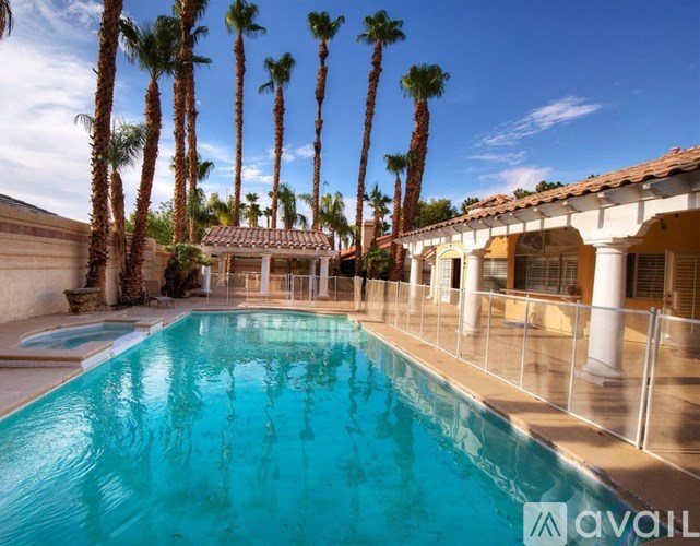 A pool surrounded by palm trees and a white building.