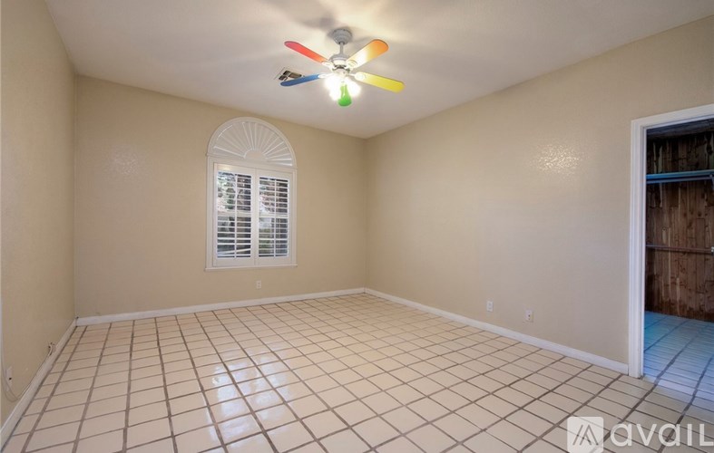 A room with a ceiling fan and tile flooring.