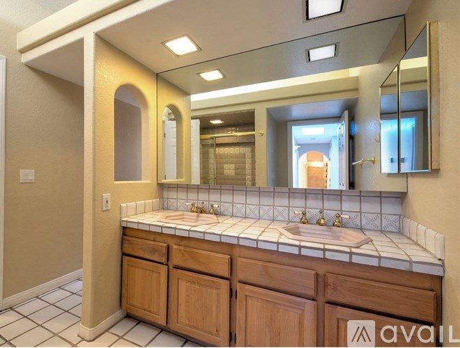 A bathroom with a sink, mirror, and wooden cabinets.