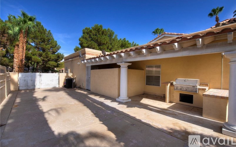 A sunny day at a house with a driveway and a covered patio.