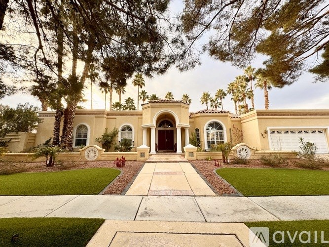 A large house with a driveway and trees in front.