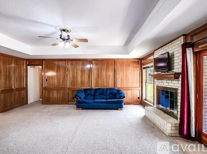 A living room with a blue couch and a fireplace.