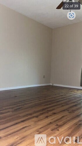 A room with wooden flooring and a wall with a window.