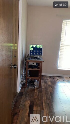 A room with a computer on a desk and a window with blinds.