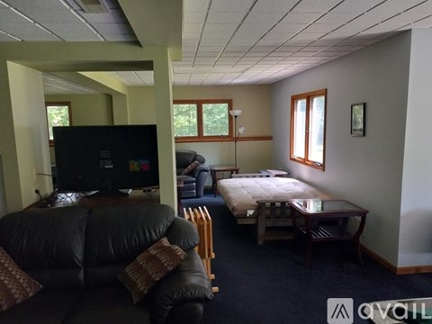 A living room with a black leather couch and a television.