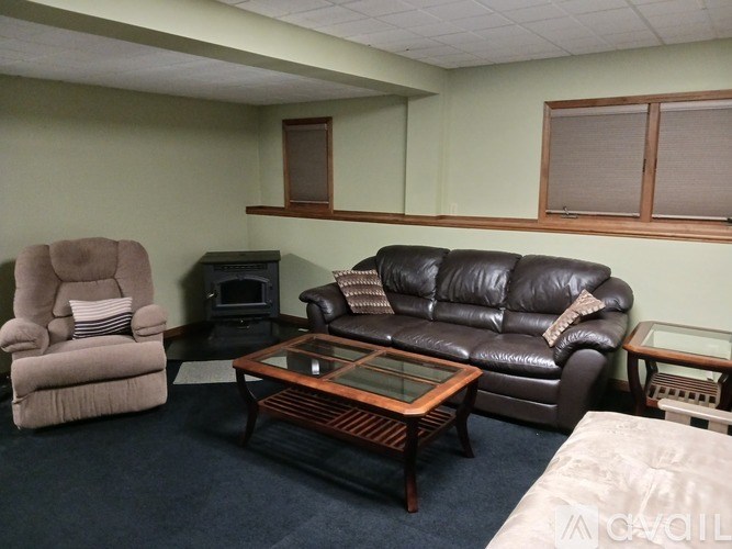A living room with a brown leather couch, a beige recliner, and a wooden coffee table.