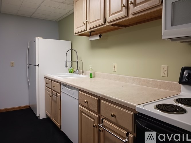 A kitchen with a white fridge, wooden cabinets, and a black stove top.