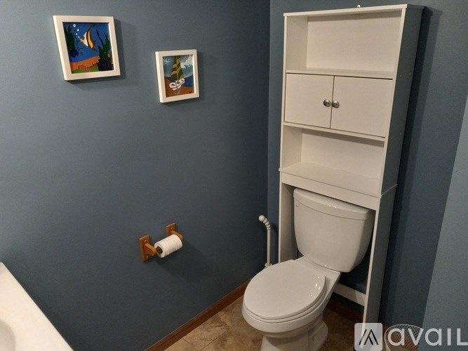 A white toilet is in a bathroom with blue walls.