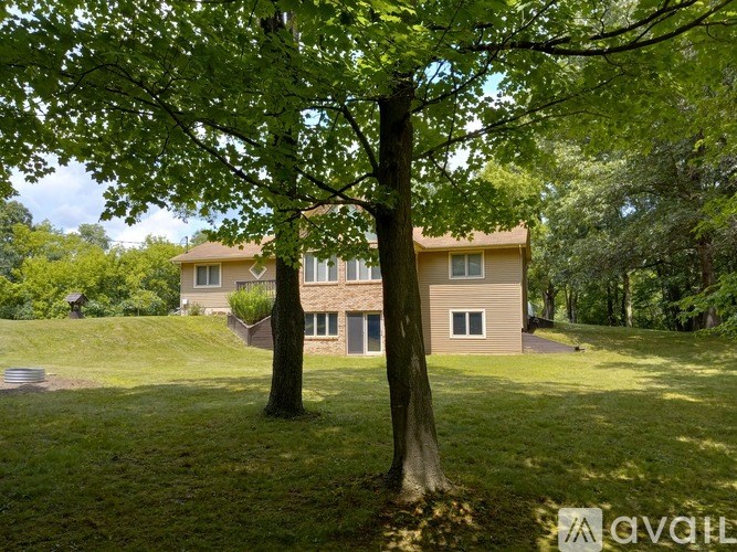 A house is surrounded by trees in a grassy area.
