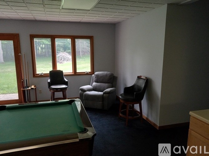 A room with a pool table and chairs.