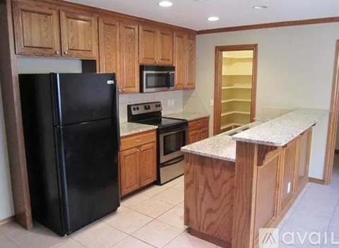 A kitchen with wooden cabinets and a black refrigerator.