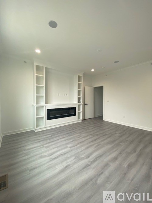 A spacious room with a fireplace and built-in shelves.