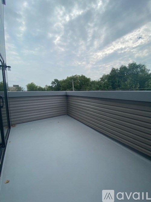 A balcony with a metal railing and a closed grey shutter.