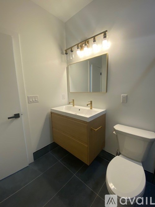 A bathroom with a toilet, sink, and mirror.