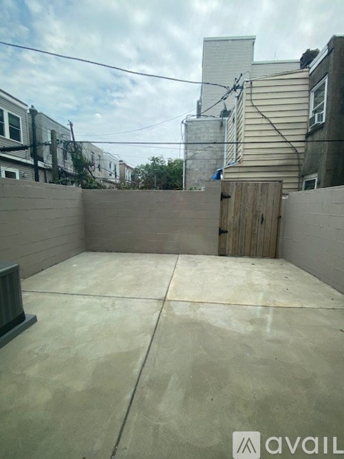 A backyard with a concrete floor and a wooden fence.