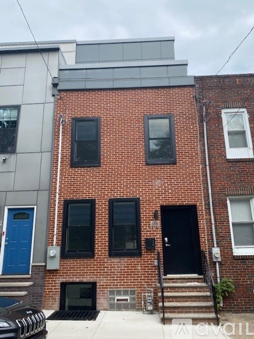 A red brick building with a black door and a blue door.