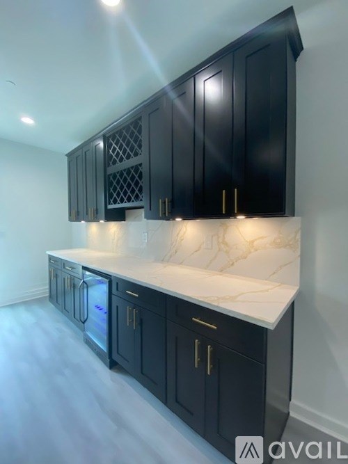 A kitchen with black cabinets and a marble countertop.