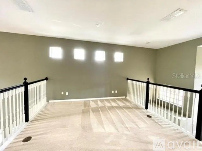 A spacious room with a wooden floor and a balcony with black railings.