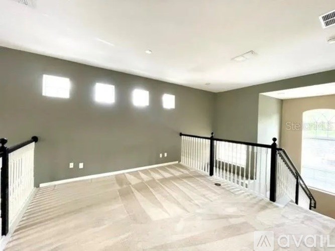 A spacious room with a checkered floor and a staircase with black railings.