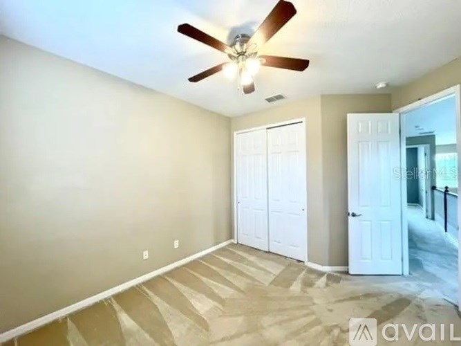 A room with a ceiling fan and carpeted floor.