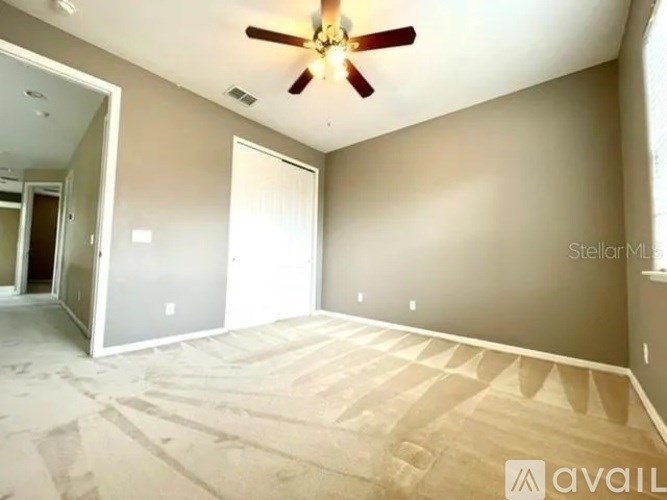 A room with a ceiling fan and a carpeted floor.