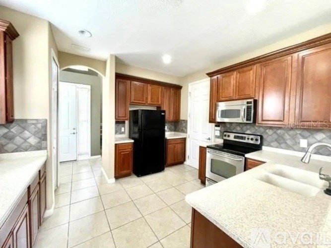A kitchen with brown cabinets and black appliances.