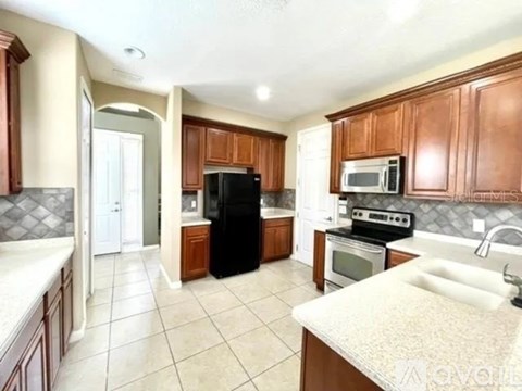 A kitchen with brown cabinets and black appliances.