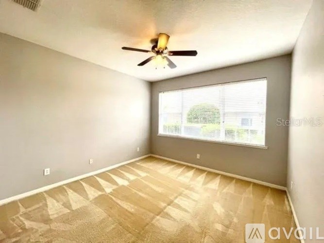 A room with a ceiling fan and a window with blinds.