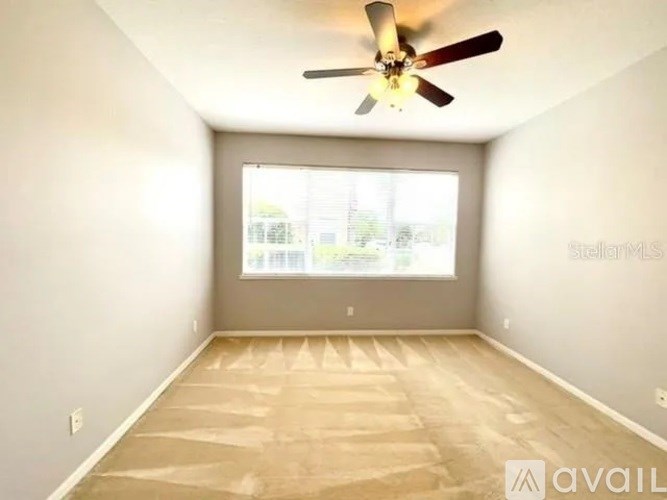 A room with a ceiling fan and a window with blinds.