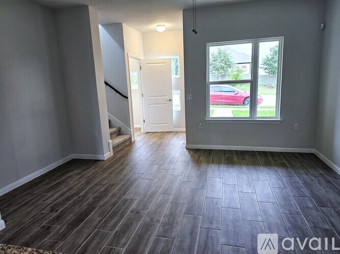 A room with a wooden floor and a window showing a red car outside.