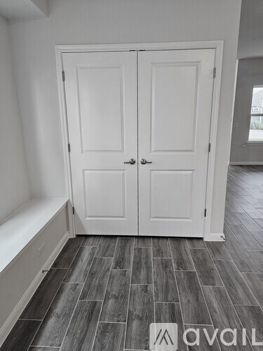 A white double door is in a room with a wooden floor.