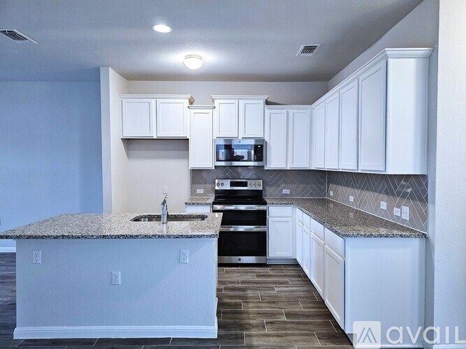 A kitchen with white cabinets and a granite countertop.