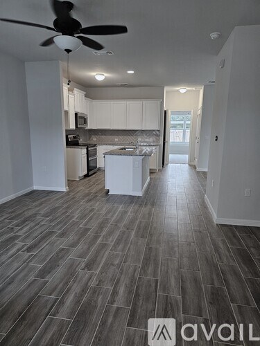 A spacious kitchen with a fan and wooden flooring.