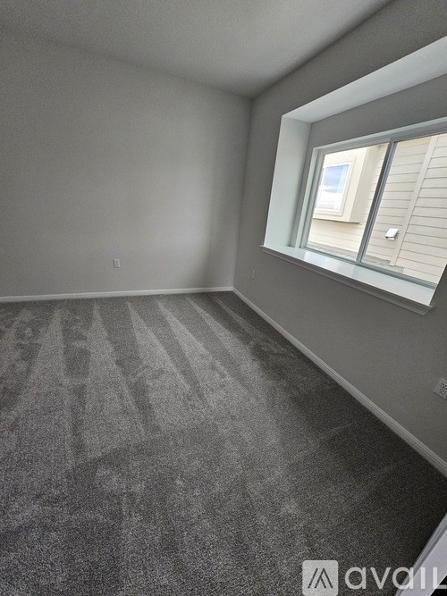A room with a carpeted floor and a window with blinds.