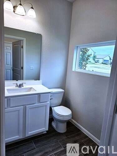 A bathroom with a toilet, sink, and mirror.