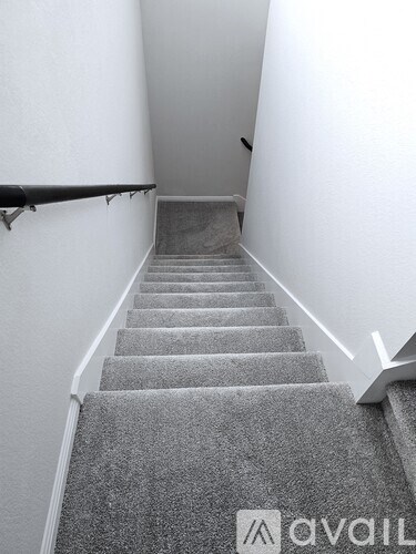 A staircase with a carpeted runner and a metal handrail.