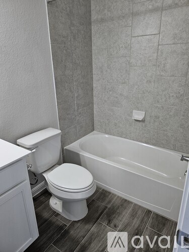 A white toilet sits next to a white bathtub in a bathroom.