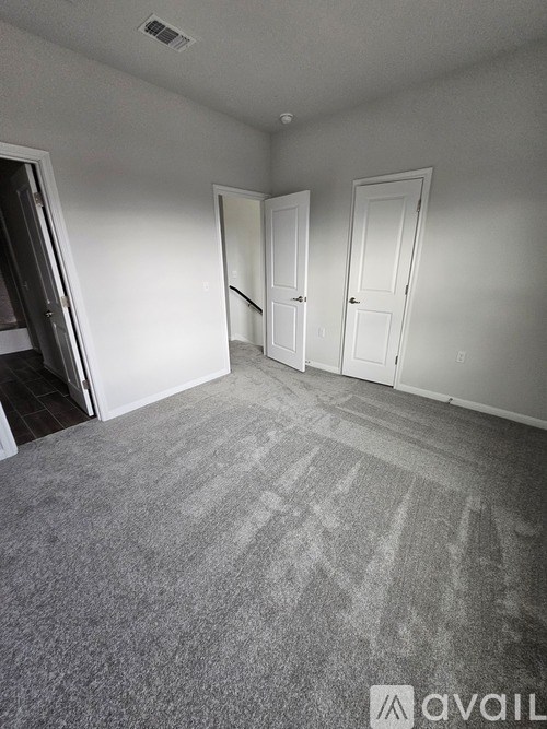 A room with a carpeted floor and three doors.
