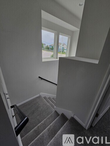 A staircase with a carpeted runner and a black handrail.