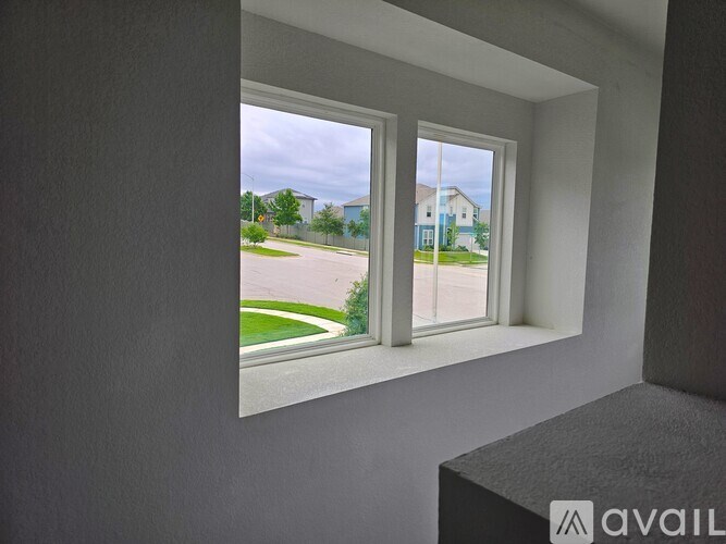 A view from inside a room looking out through a window at a street with houses.