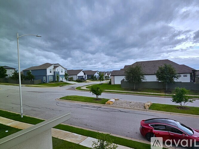 A suburban street with a red car parked on the side.