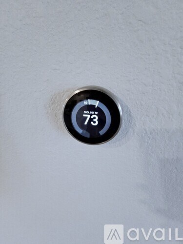 A thermostat showing 73 degrees on a white wall.